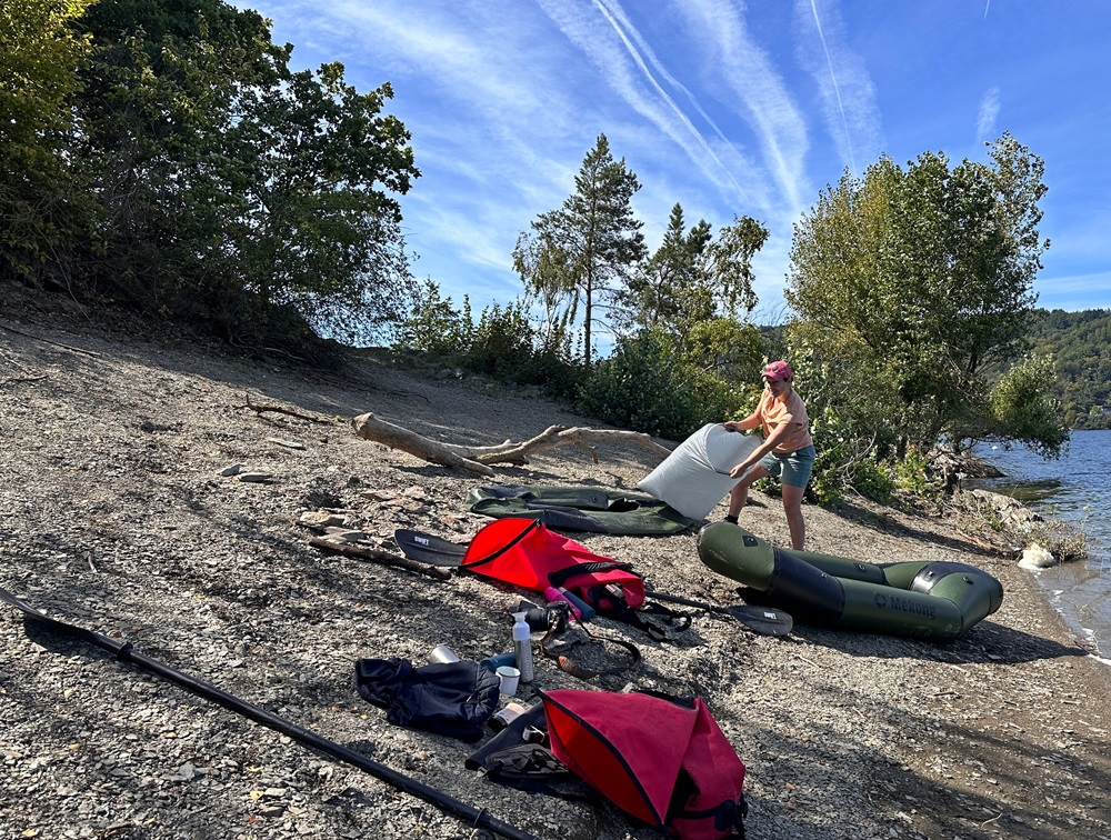 Gonfiare un packraft sulla riva del lago durante un'avventura di packrafting nell'Eifel, in Germania